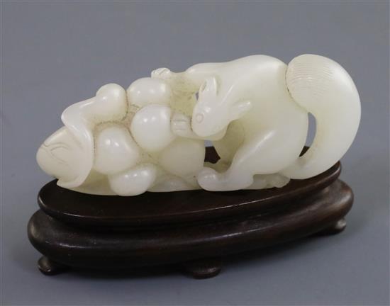 A Chinese white jade carving of a squirrel, grapes and lotus leaf, 18th/19th century, L. 6.4cm, wood stand